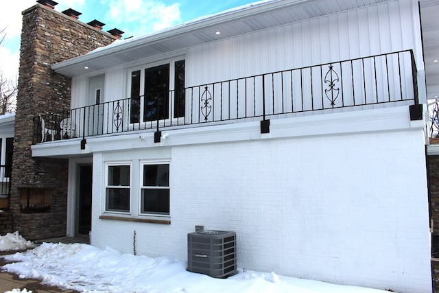 view of snow covered exterior with cooling unit and a balcony