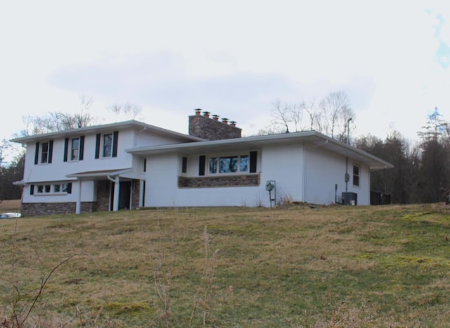 tri-level home featuring central AC unit, stucco siding, stone siding, and a chimney