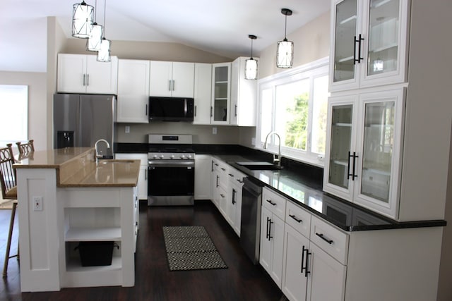 kitchen featuring sink, white cabinets, hanging light fixtures, stainless steel appliances, and a center island with sink