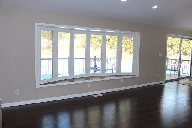 empty room with recessed lighting, baseboards, dark wood finished floors, and visible vents