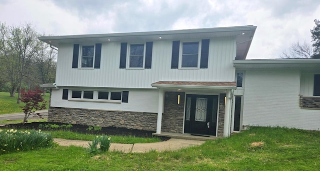 split level home featuring a front yard and stone siding