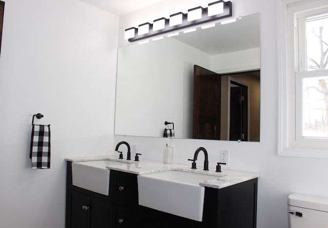 bathroom featuring a sink, toilet, and double vanity