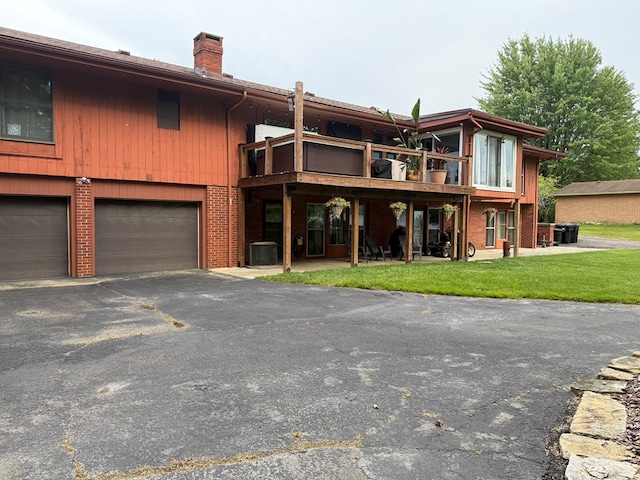 380 Tidd Dr, Galion, OH 44833 - back of property featuring a chimney, brick siding, a garage, a lawn, and asphalt driveway
