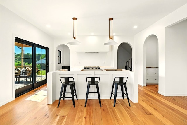 1360 Lexington Ontario Rd, Mansfield, OH 44904 - kitchen with arched walkways, light wood finished floors, a breakfast bar, recessed lighting, and pendant lighting