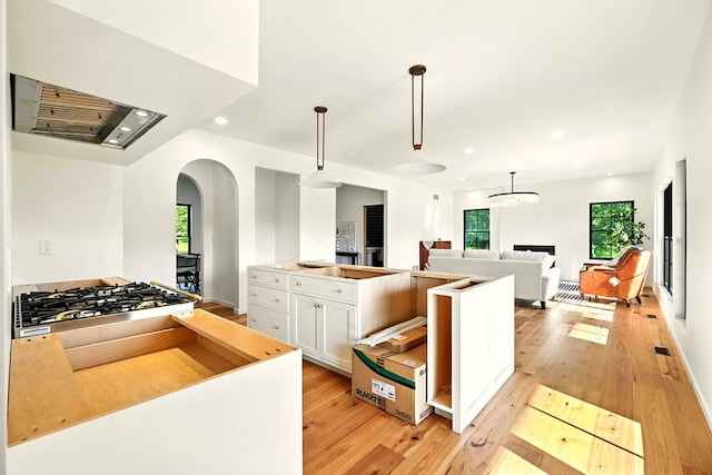 1360 Lexington Ontario Rd, Mansfield, OH 44904 - kitchen featuring arched walkways, stainless steel gas cooktop, range hood, white cabinets, and light wood-style flooring