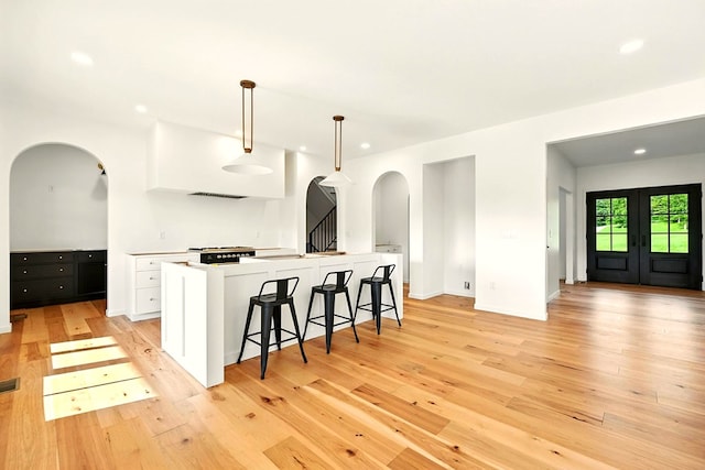1360 Lexington Ontario Rd, Mansfield, OH 44904 - kitchen featuring arched walkways, white cabinetry, light wood finished floors, recessed lighting, and a kitchen breakfast bar