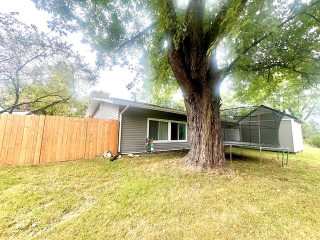 back of house with a lawn and a trampoline