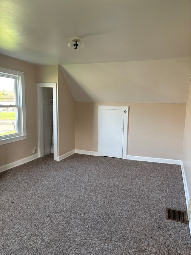 bonus room with vaulted ceiling, dark colored carpet, visible vents, and baseboards