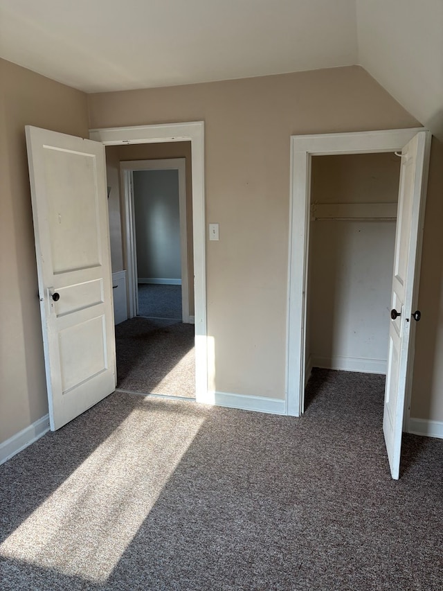 unfurnished bedroom with baseboards, dark colored carpet, and a closet
