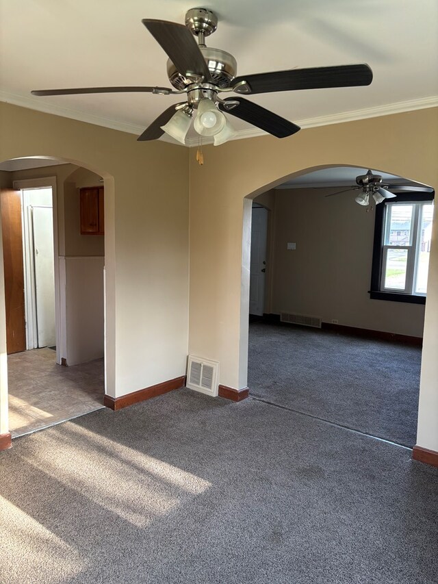 unfurnished room featuring arched walkways, visible vents, a ceiling fan, dark carpet, and ornamental molding
