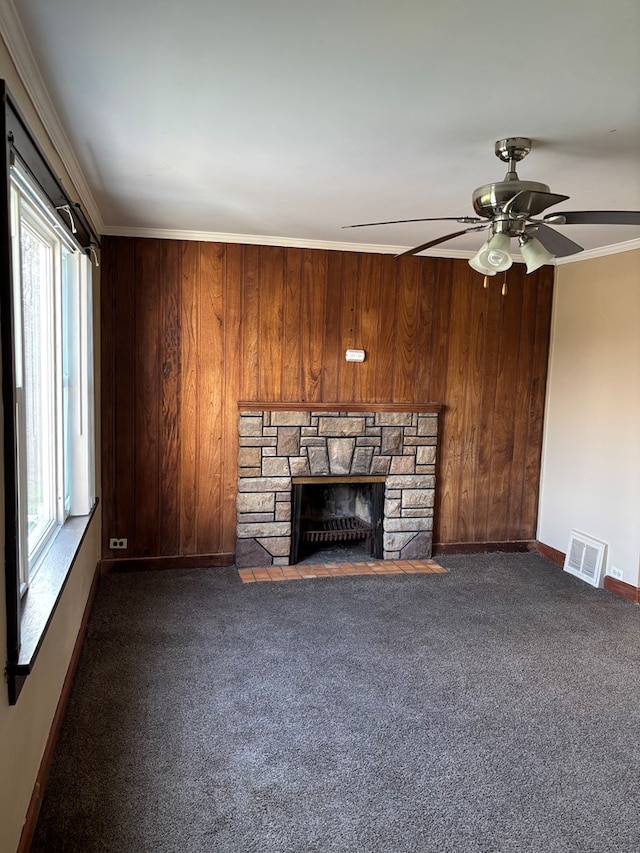unfurnished living room with wooden walls, visible vents, a fireplace, and a healthy amount of sunlight