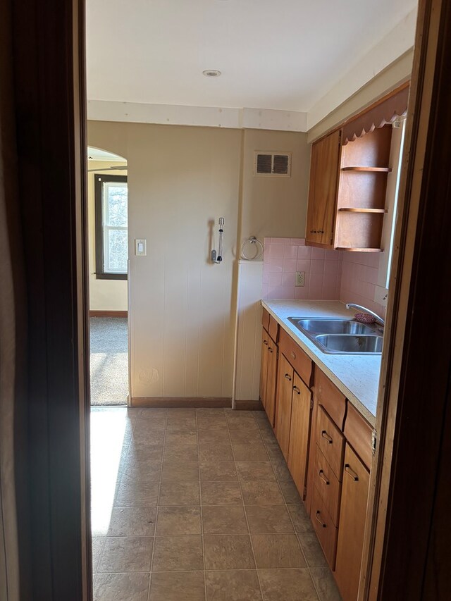 kitchen with open shelves, light countertops, visible vents, a sink, and decorative backsplash