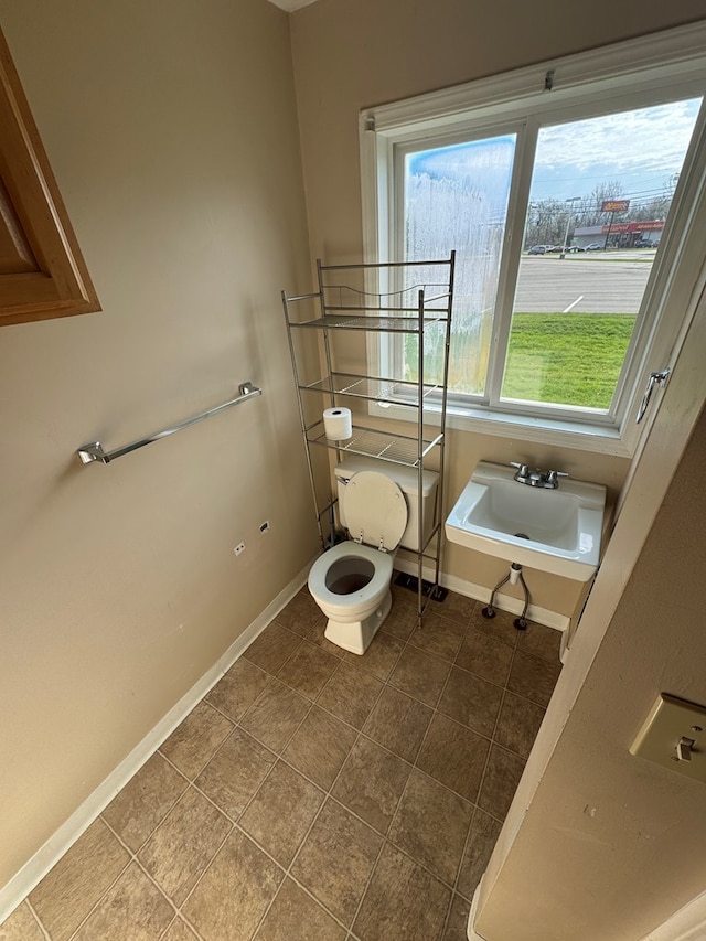 bathroom featuring baseboards, tile patterned flooring, a sink, and toilet