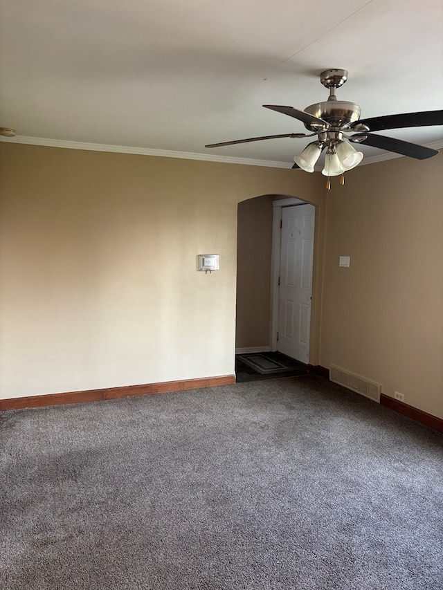 spare room featuring dark carpet, visible vents, a ceiling fan, arched walkways, and crown molding