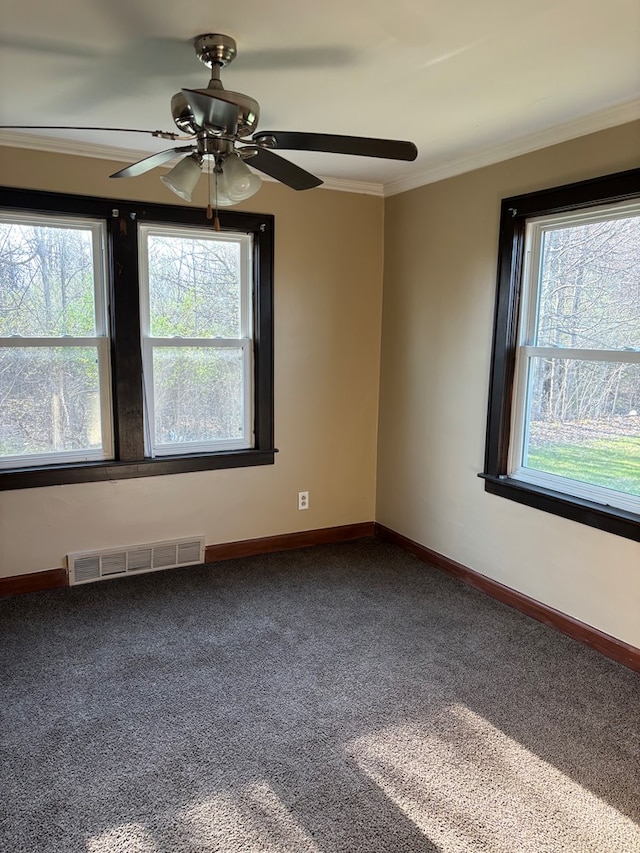 unfurnished room featuring dark colored carpet, baseboards, visible vents, a ceiling fan, and ornamental molding