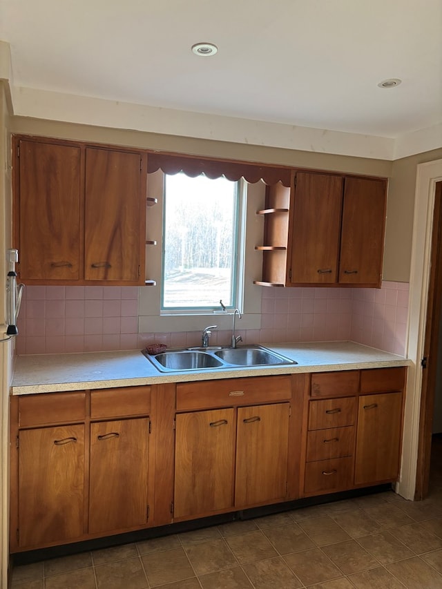 kitchen featuring open shelves, brown cabinetry, and a sink