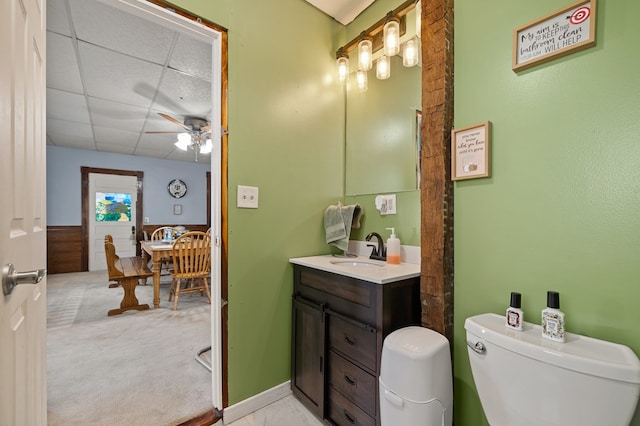 bathroom featuring a paneled ceiling, ceiling fan, vanity, and toilet