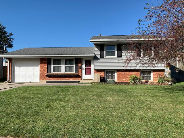 1149 Robinhood Dr, Bucyrus, OH 44820 - tri-level home featuring a garage, brick siding, a front lawn, and concrete driveway