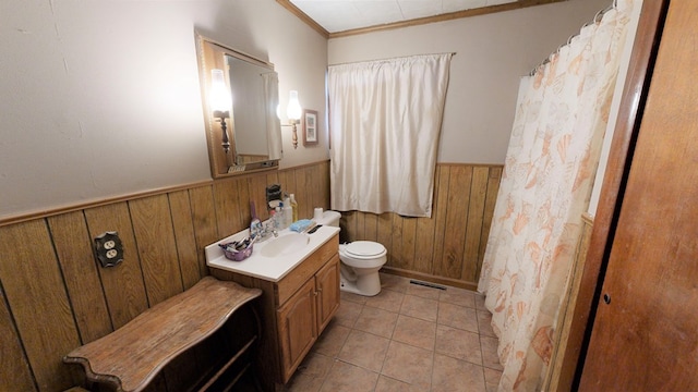bathroom with wood walls, vanity, toilet, crown molding, and tile patterned floors