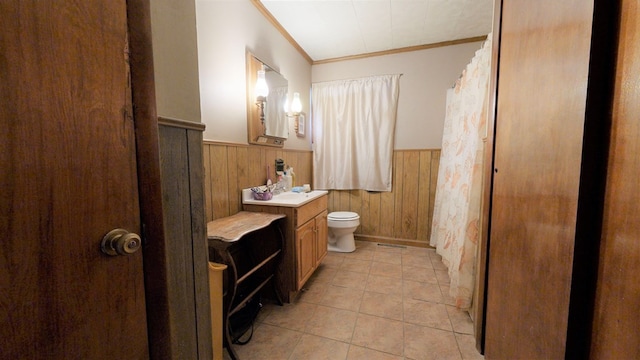 bathroom with toilet, wood walls, crown molding, vanity, and tile patterned flooring