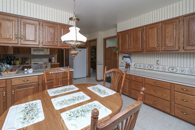 kitchen with white appliances, brown cabinets, light countertops, and wallpapered walls