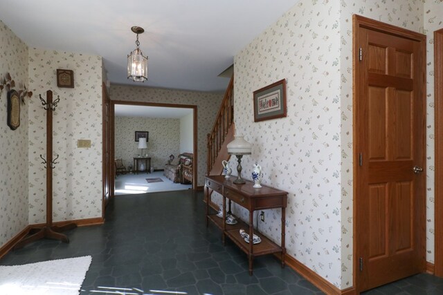 hall with baseboards, stairs, and wallpapered walls