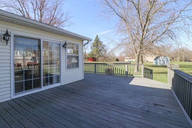 wooden terrace featuring a lawn, a storage unit, and an outdoor structure