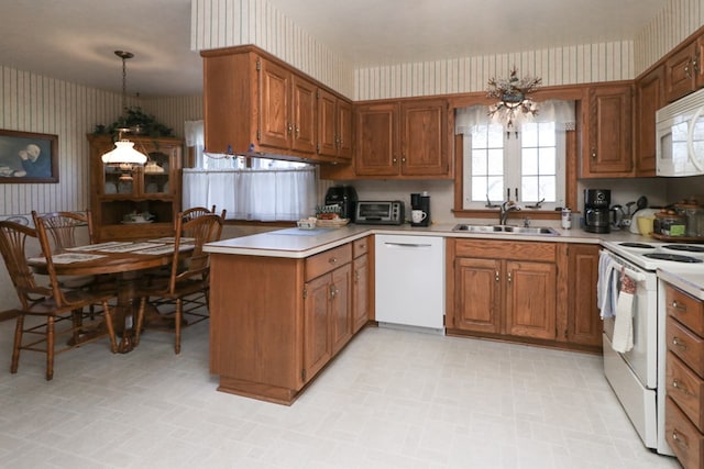 kitchen featuring wallpapered walls, brown cabinets, a peninsula, white appliances, and a sink