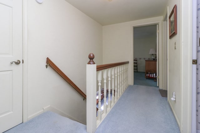 hall with an upstairs landing, baseboards, and carpet floors