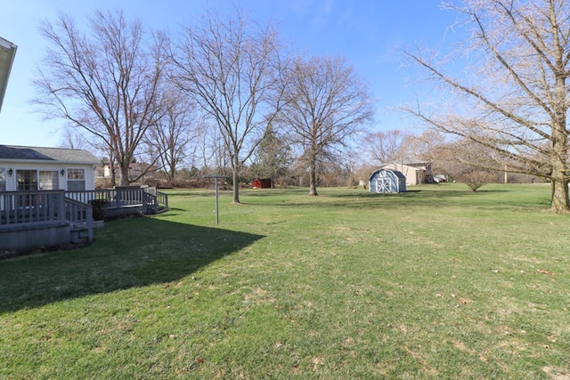 view of yard featuring a wooden deck, an outbuilding, and a storage shed