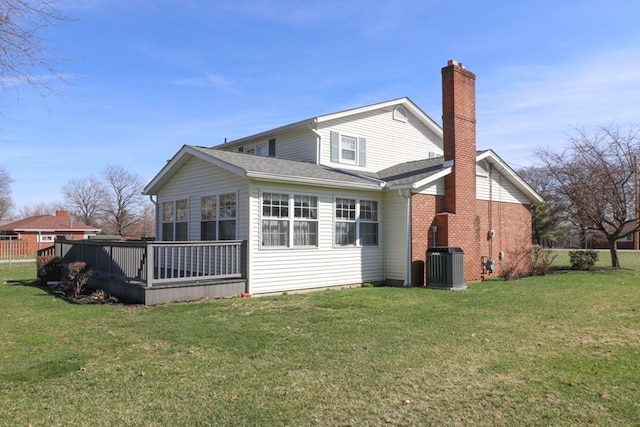 back of property featuring a wooden deck, central AC, roof with shingles, a lawn, and a chimney