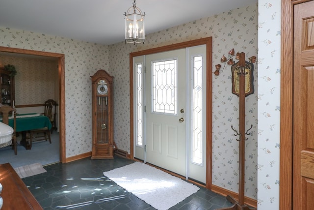 entrance foyer featuring wallpapered walls, a notable chandelier, and baseboards