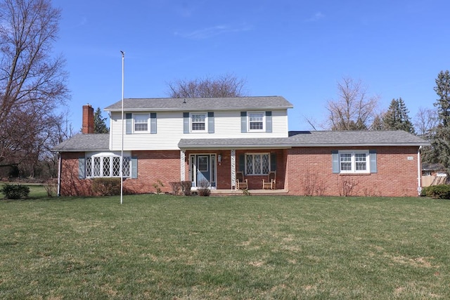 traditional-style house with a front yard, brick siding, roof with shingles, and a chimney