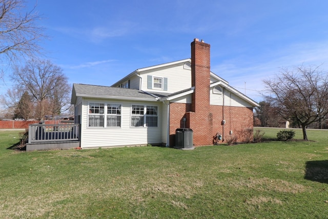 back of property with brick siding, cooling unit, a chimney, and a yard