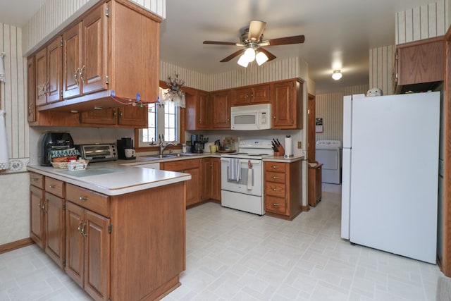 kitchen with washer / dryer, white appliances, wallpapered walls, and a peninsula