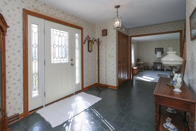 entrance foyer with baseboards, stone finish floor, and wallpapered walls