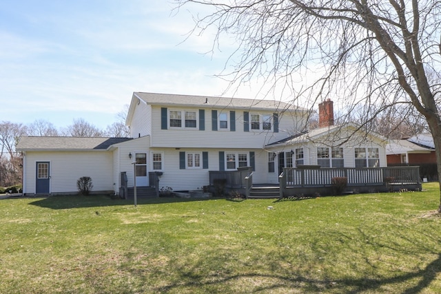 rear view of property with a lawn, entry steps, a chimney, and a deck