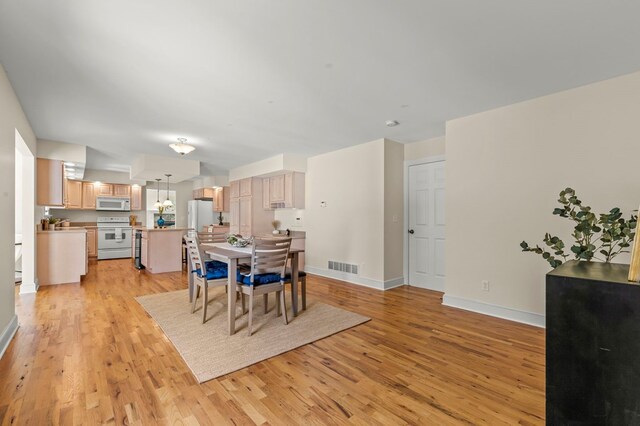 dining area featuring baseboards, light wood-style floors, visible vents, and an inviting chandelier