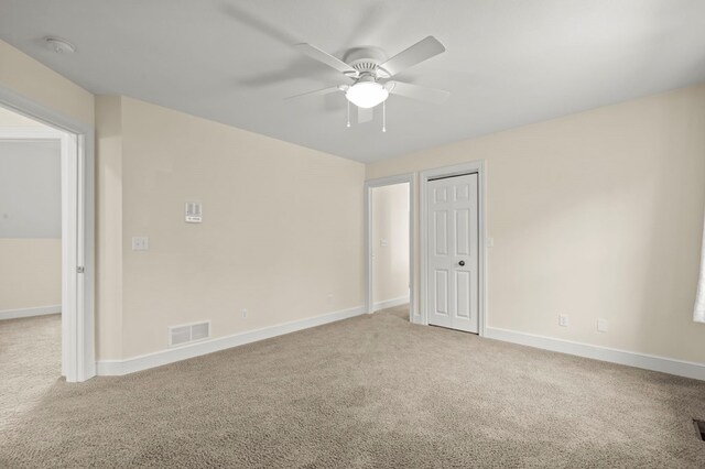 carpeted spare room with baseboards, a ceiling fan, and visible vents