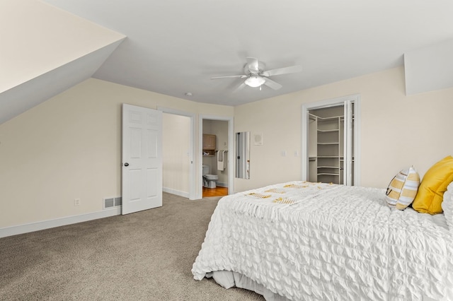 carpeted bedroom with a closet, a spacious closet, ensuite bath, baseboards, and visible vents