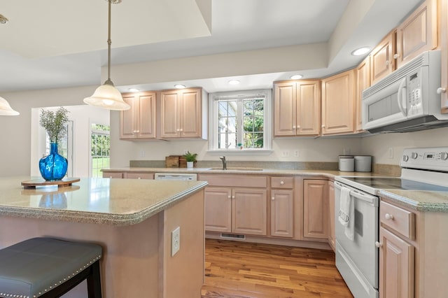 kitchen featuring recessed lighting, light brown cabinetry, a sink, and white appliances