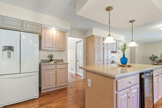 kitchen featuring light wood-style floors, white refrigerator with ice dispenser, light stone countertops, a kitchen island, and hanging light fixtures