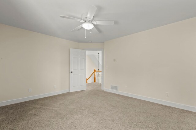 empty room with visible vents, light carpet, baseboards, and ceiling fan