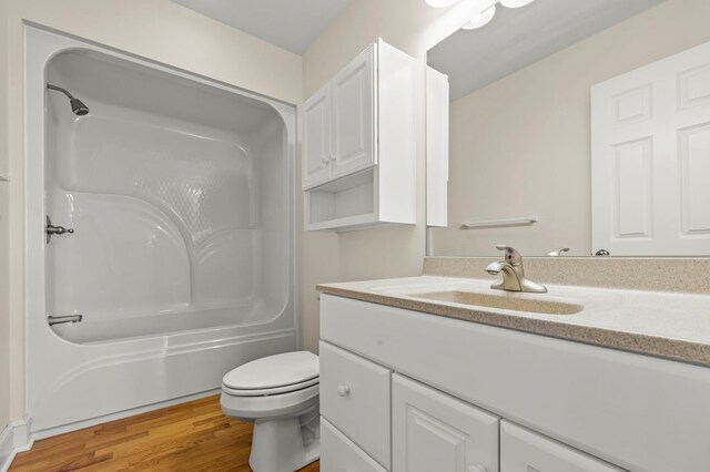 bathroom featuring wood finished floors, toilet, vanity, and  shower combination