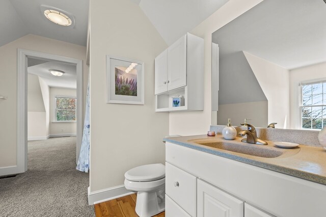 bathroom with lofted ceiling, toilet, vanity, and baseboards