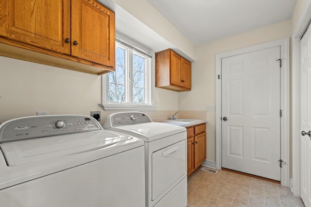 clothes washing area featuring washer and clothes dryer, a sink, cabinet space, baseboards, and visible vents