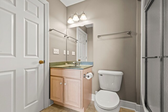 bathroom with vanity, tile patterned flooring, a shower with shower door, and toilet
