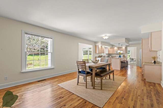 dining space with baseboards, light wood finished floors, and visible vents