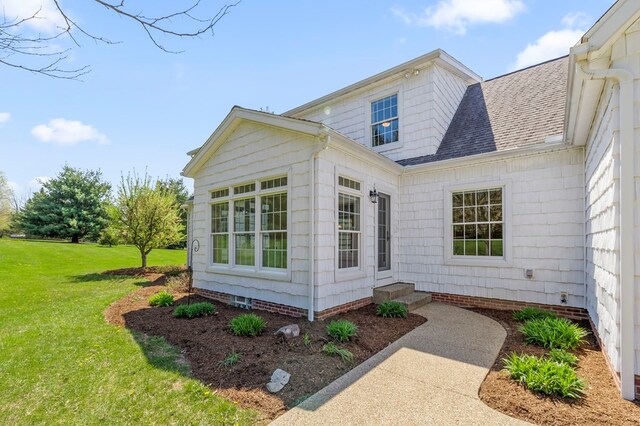 view of side of property featuring a lawn, roof with shingles, and crawl space