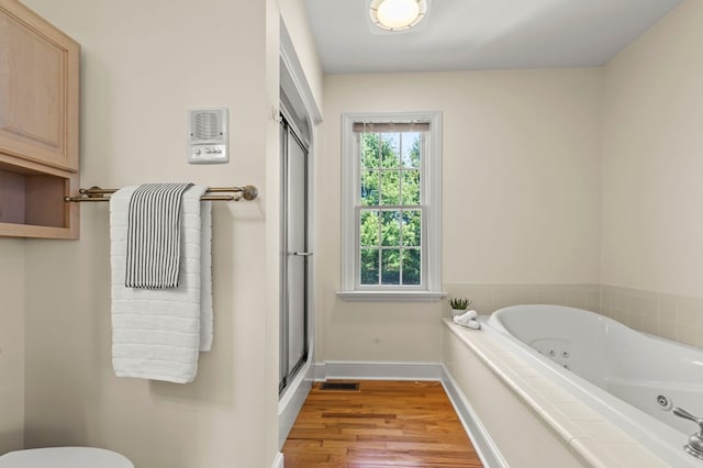 full bathroom with a whirlpool tub, wood finished floors, visible vents, baseboards, and a stall shower